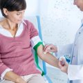 Healthcare worker preparing to take blood from middle aged woman 